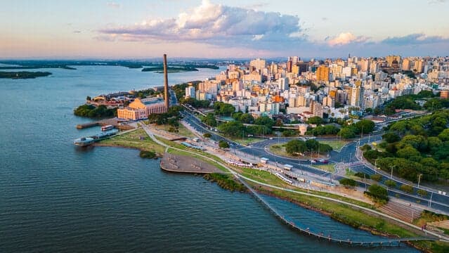 Aerial view of the Gasômetro power plant and its chimney on the Guaíba waterfront, with the city skyline behind it