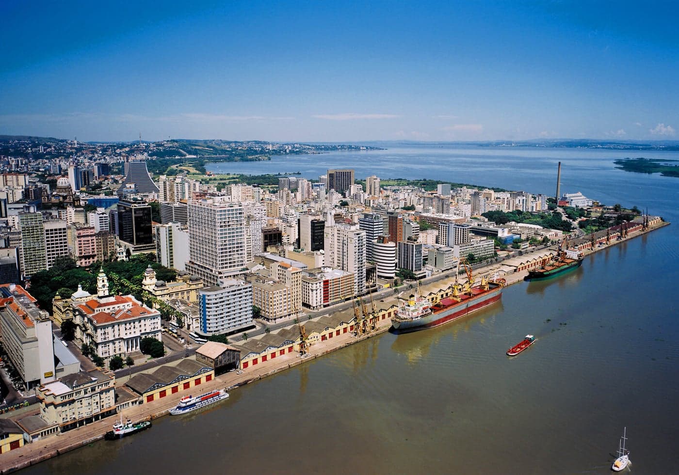 Aerial view of the historic centre along the port, with cargo ships docked beside the warehouse sheds on the Guaíba