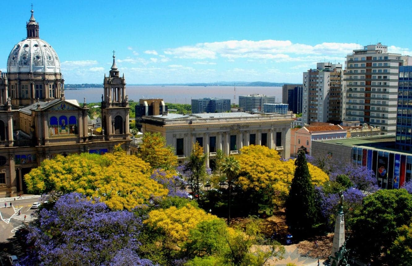 Praça da Matriz in bloom, with the cathedral dome on the left and purple and yellow trees over the square